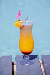 A nice cocktail, hat and sunglasses by the pool