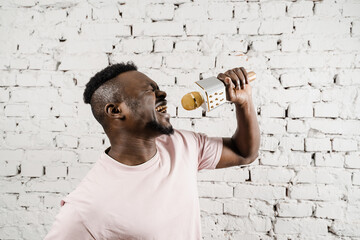 Handsome and cheerful singer is performing his song. Recording the audio in the studio. Young...