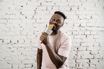 Young african man is enjoying singing in the microphone. Handsome and cheerful singer is performing...