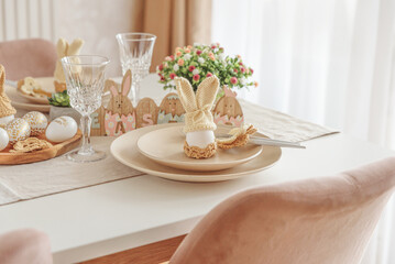Festive Easter table setting with Easter bunny made from egg and knitted ears. Easter celebration concept