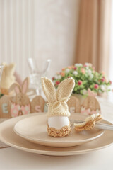 Close-up festive Easter table setting with Easter bunny made from egg and knitted ears. Easter celebration concept