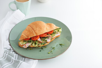 Croissant toast with lettuce, cheese, ham and microgreens on white table. Healthy breakfast. Top view