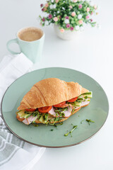 Croissant toast with lettuce, cheese, ham and microgreens on white table. Healthy breakfast. Top view