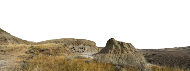 A prominent dry sandy desert mound surrounded by a badlands setting and a transparent sky.
