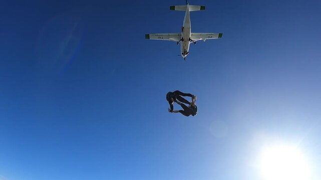 A couple of skydivers jump out of the plane, on a summer day.