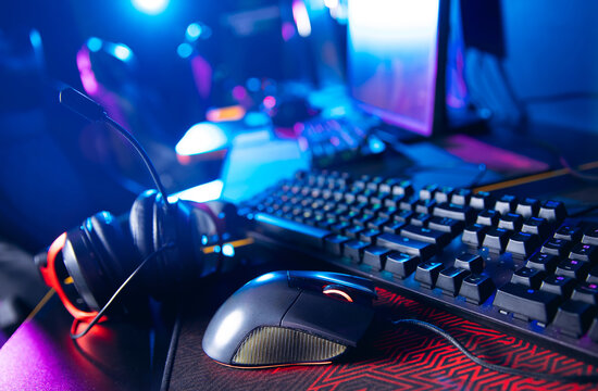 Gaming setup with mechanical keyboard, rgb mouse, and headset in neon lighting