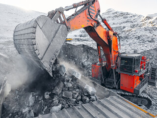 Open pit coal mining with excavator loading rocks to truck, aerial view
