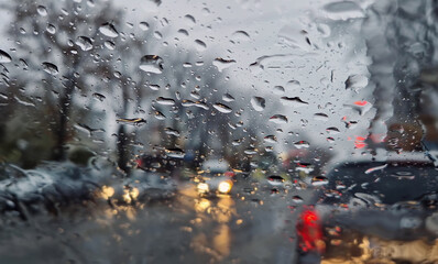 Melted snow and rain drops on the windshield of a car. Blurred outdoor view, winter season sleet as...