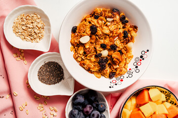 Healthy breakfast ingredients with handmade granola and fruits mango, papaya and grapes