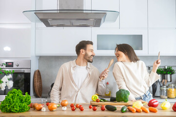 A couple shares a lighthearted moment in a modern kitchen, embodying love and creativity through their cooking activities.