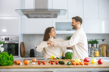 In a bright kitchen full of fresh ingredients, a couple enjoys a joyful cooking session, sharing smiles and love through food.