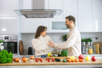 In a stylish kitchen, a happy couple shares a moment of love while preparing fresh ingredients for a delightful meal together.