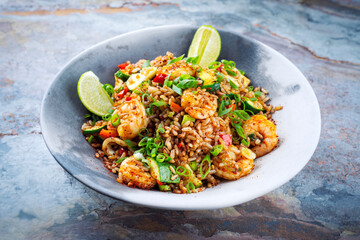 Stir-Fried spicy red parboiled rice with king prawns, seafood and vegetable in an Asia style bowl