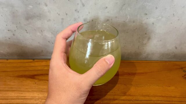 Hand holding and shaking a glass of iced green tea