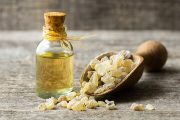 Glass bottle of frankincense essential oil with aromatic resins on rustic background, herbal...