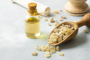 Glass bottle of frankincense essential oil with aromatic resins on rustic background, herbal...