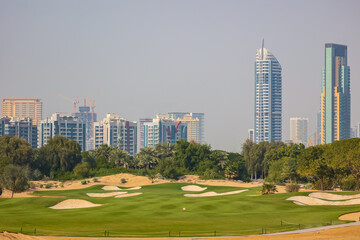 Obraz premium A lush golf course with sand bunkers and green fairways, set against a backdrop.