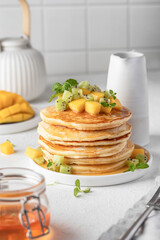 Pancakes with fruit and honey in plate on white background. Delicious dessert for Maslenitsa or Pancake Day. Healthy breakfast
