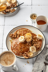 Healthy oatmeal pancakes with banana, nuts and honey on white tile background. Morning food breakfast concept. Pancake day or Maslenitsa recipe
