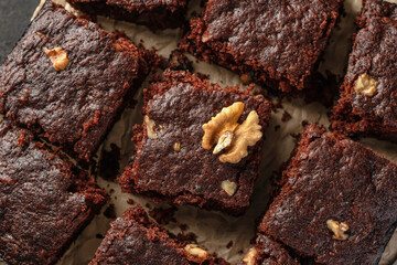 Chocolate brownie cake dessert with nuts on baking rack on dark background top view