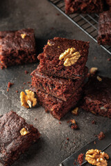 Stack of delicious brownie pieces with hazelnuts on dark background
