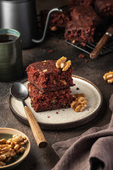 Stack of delicious brownie pieces with hazelnuts on a plate dor breakfast on dark background