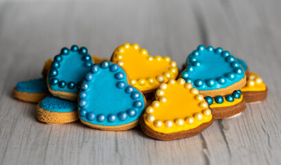 Valentine’s day composition with cookies in shape of hearts decorated by yellow and blue icing and sprinkles on towel embroidered with Ukrainian ornament