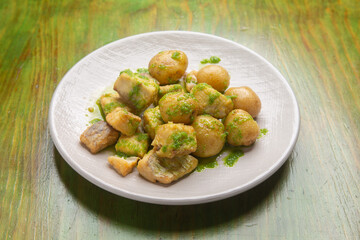 Delicious fried fish seasoned with green sauce and served with potatoes on a plate