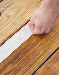 Hand is applying a strip of paper to a wooden floor