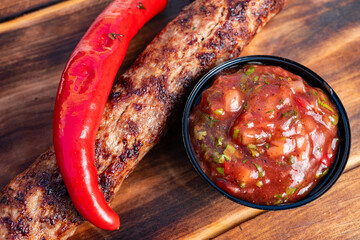 Grilled sausage and spicy salsa served with fresh chili pepper