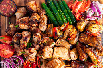 Grilled assorted meats and vegetables served on a wooden platter