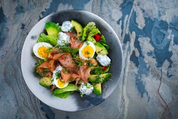 Traditional German mixed salad with graved salmon glavlax, eggs and avocado served as top view in a Nordic design bowl