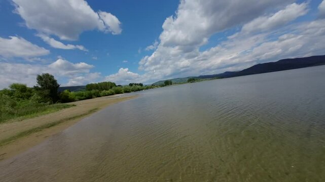 Drone flying over Olt River in Romania with green surroundings