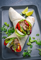 Italian style wrap piada wheat tortilla with tuna fish, vegetable and hardboiled egg served as closeup on a tray