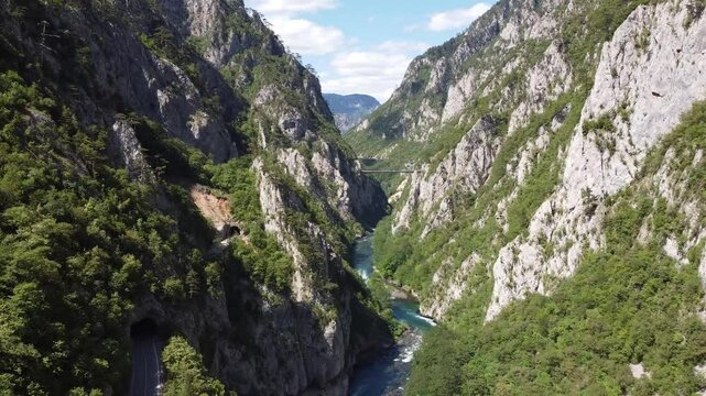 Narrow gorge of Piva river canyon close to the high road bridge over the valley. Green vertical rock formations and blue sky in the background, close to durmitor and Mratinje hydroelectric dam.