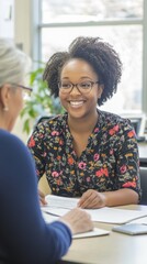 A social worker smiles warmly while discussing important matters with a client in a contemporary office. The atmosphere promotes trust and open communication