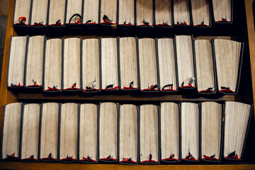 A row of hymn books with red bookmarks on a wooden shelf inside a church. A symbolic representation of faith, tradition, and religious devotion. Ideal for spiritual, educational, and cultural themes
