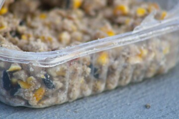 open bird feed packet with chunks of corn and seeds