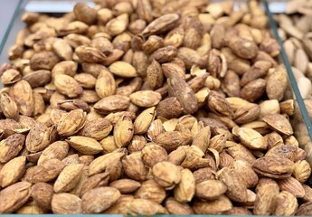 Roasted delicious inshell almonds with spices in large quantities for sale at the vegetable market. Close-up