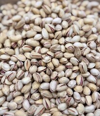 A lot of fried selected clean delicious pistachios for sale in a box at a local specialty market. Close-up