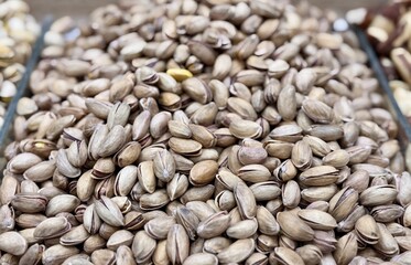 A lot of fried selected clean delicious pistachios for sale in a box at a local specialty market. Close-up