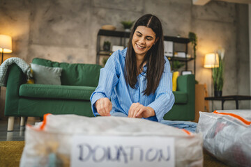 One woman caucasian adult at home choose clothes for charity donation