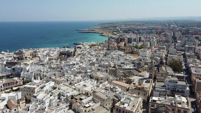 Wide drone panorama of the city of Monopoli on italian coast in Puglia region on a sunny spring day. Visible port and old houses