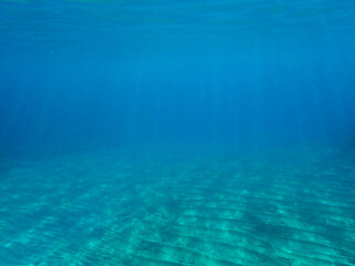 Ocean blue underwater with sunrays, Underwater Sea Deep Water Abstract Sunshine, sea wave , clean waters in summer time, Natural underwater seascape, sand on ocean floor and water surface with sunligh