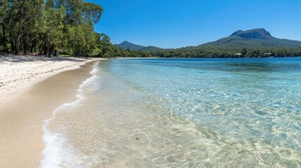 A serene beach scene with clear water, sandy shore, and lush green hills in the background.