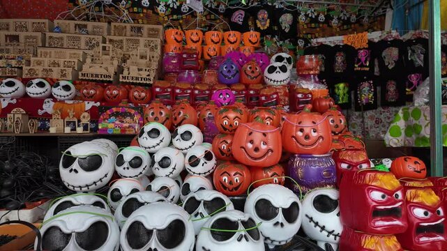 A store display of Halloween pumpkins and jack-o-lanterns. The pumpkins are of various sizes and colors, including white, orange, and black. The display is arranged in a way that creates a festive