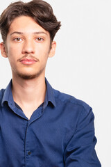 Young handsome student in blue shirt looking seriously at camera. Isolated on white background. Confident person.