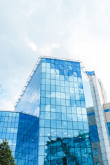 Modern glass office building reflecting the sky and surrounding cityscape. The blue-tinted windows contrast with the clean architectural lines.