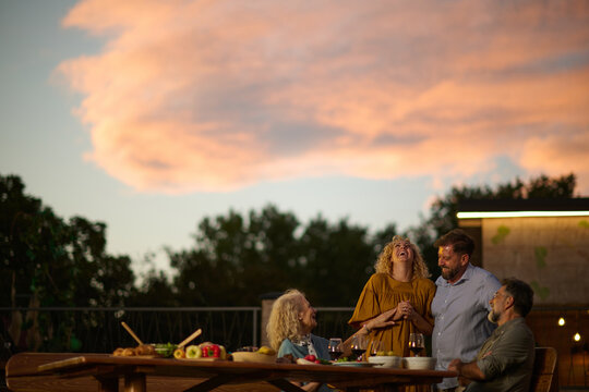 Friends having dinner together on rooftop at sunset