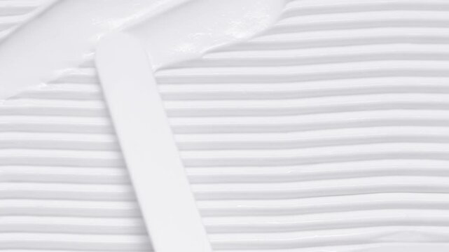 Close up of spatula smear cream texture, skincare stroke background. Cosmetic product swatch